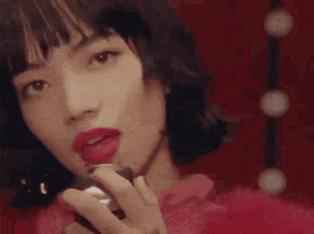 a close up of a woman with red lipstick holding a can of soda .