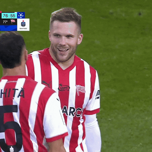 a soccer player wearing a red and white striped shirt with arc on the front