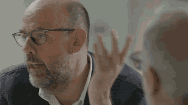 a man with glasses and a beard is talking to someone