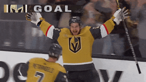 a hockey player celebrates a goal with his arms in the air and the word goal behind him
