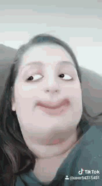a woman is making a funny face with her eyes closed and a smile on her face .