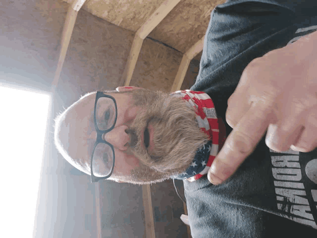 a man with glasses and a beard wears a black shirt that says ' armour ' on it