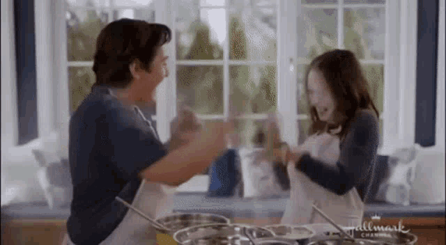 a man and a girl are dancing in a kitchen with pots and pans in the background .