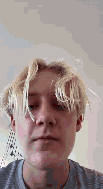 a young man with blonde hair is looking at the camera with his eyes closed