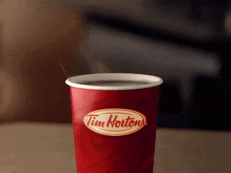 a cup of tim hortons coffee on a table with steam coming out of it