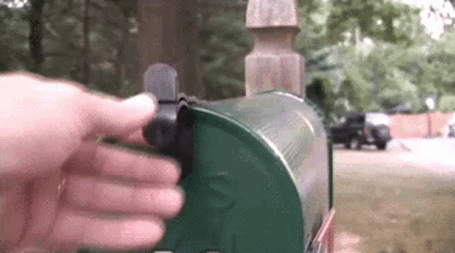a person is opening a green mailbox with the letter s on it