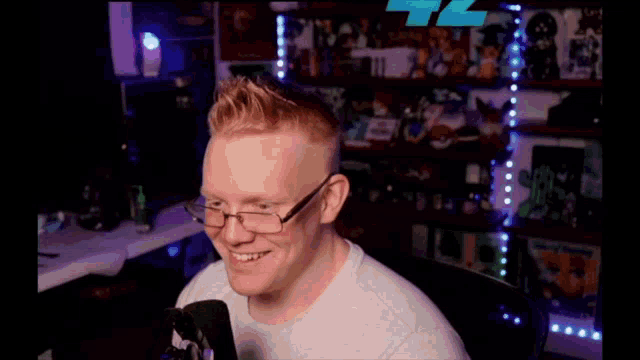 a man wearing glasses is sitting in front of a microphone and smiling