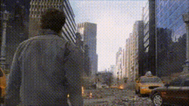 a man is walking down a city street with taxis in the background
