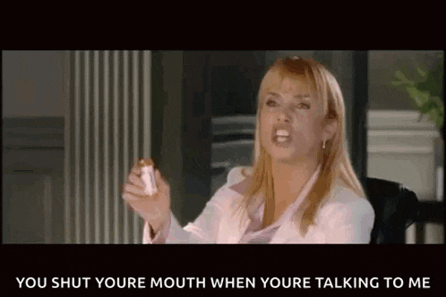 a woman in a white jacket is holding a bottle and saying " you shut youre mouth when you 're talking to me