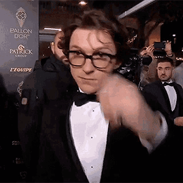 a man in a tuxedo and bow tie is pointing at something
