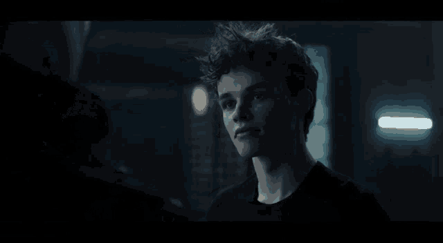 a man and a boy are standing next to each other in a dark room .