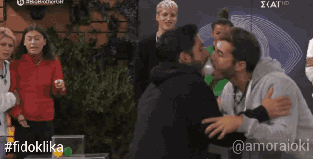 two men kissing in front of a sign that says big brother gr