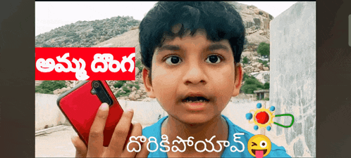 a young boy is holding a red cell phone in front of a sign that says ' telugu '
