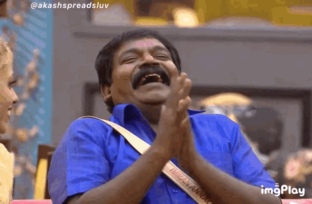 a man in a blue shirt is clapping his hands and has a strap that says ' india ' on it