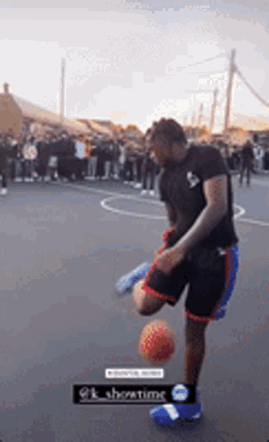 a man is kicking a basketball on a court with a crowd in the background