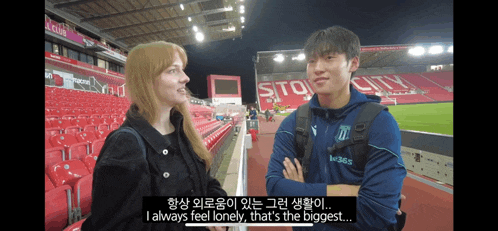 a man and a woman are talking in a stadium with a sign that says stg city