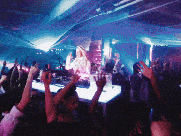 a woman is standing in front of a crowd at a party