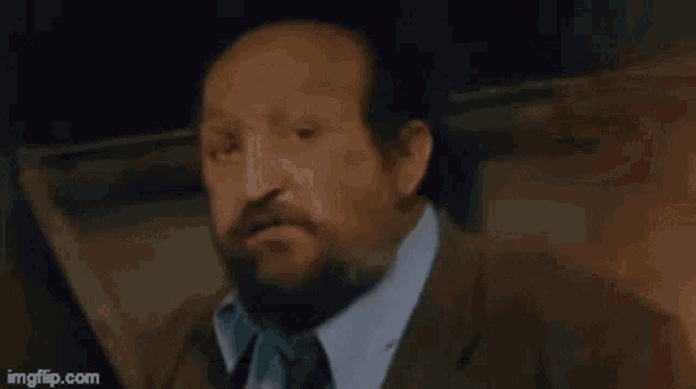 a man with a beard is talking in a foreign language and has the word lakesh on his face .