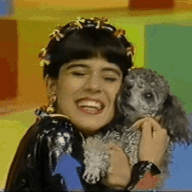 a woman is holding a poodle and smiling .