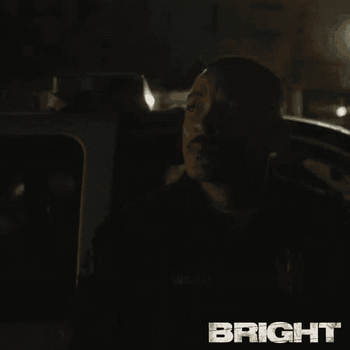 a man is sitting in the back seat of a car looking out the window .