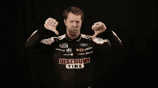 a man in a discount tire shirt giving the thumbs down sign