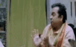 a man is clapping his hands in a room while talking to another man .