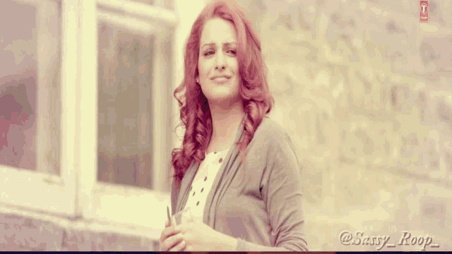 a woman with red hair is standing in front of a window with the name sassy roop written on the bottom