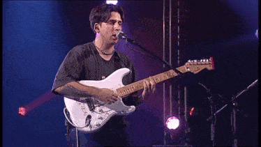 a man singing into a microphone while holding a guitar