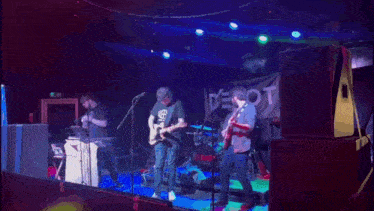 a man playing a guitar in front of a debt banner