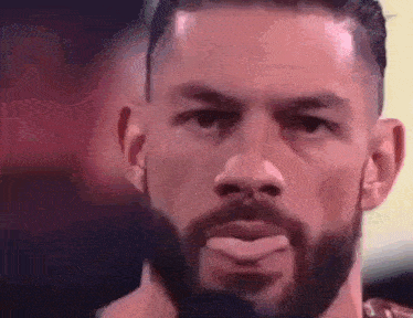 a man with a beard is making a funny face with his tongue out .