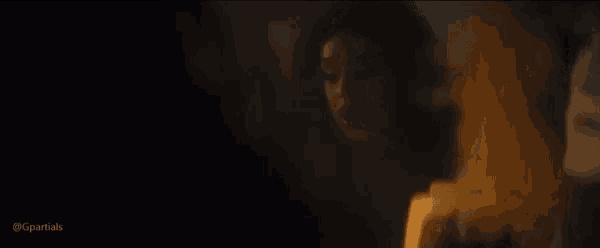 a woman is standing in front of a fire in a dark room with smoke coming out of it .