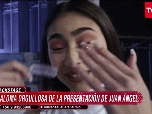 a woman wipes her eyes in front of a sign that says paloma orgullosa de la presentación de juan angel