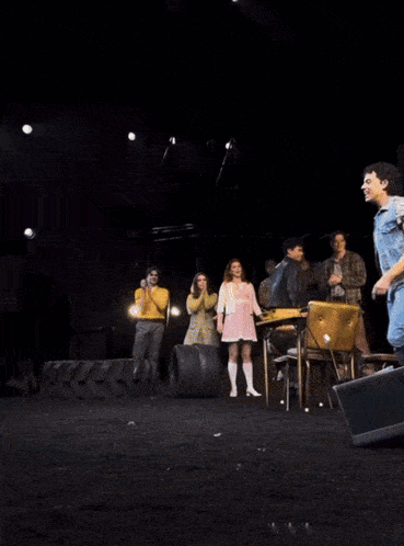 a person in a denim vest is dancing on stage