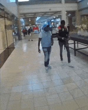 two men walking in a mall with a table in the middle