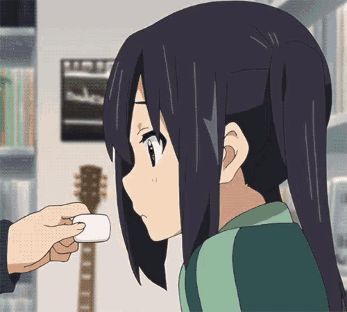 a person is holding a marshmallow over a girl 's face