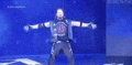 a man is standing on a stage with his arms outstretched in front of a blue background .