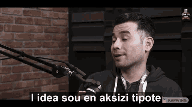a man speaking into a microphone with the words " i idea sou en aksizi tipote " on the screen