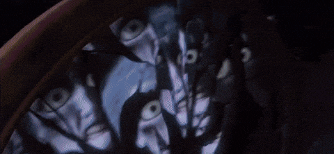 a person with a hood on their head is standing in a dark room