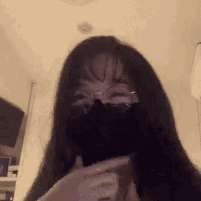 a woman wearing a mask and glasses is making a face .