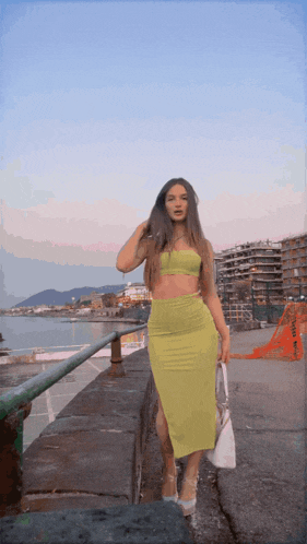 a woman in a yellow dress stands on a sidewalk