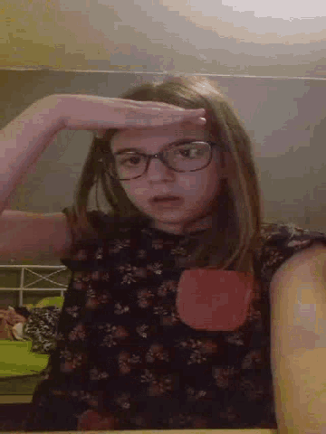 a young girl wearing glasses is making a funny face .