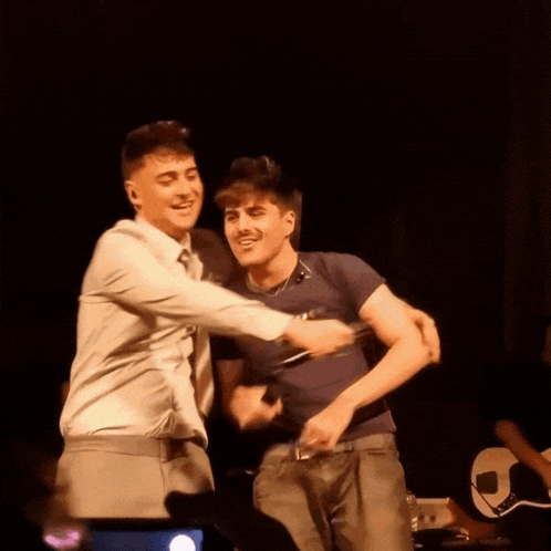 two men are hugging each other on a stage and one of them is wearing a shirt that says ' i love you '