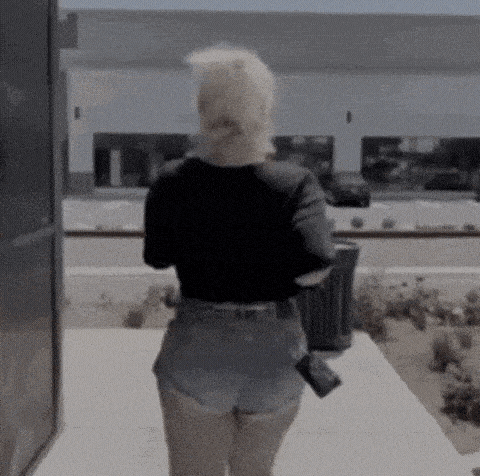 a woman in shorts is walking down a sidewalk .