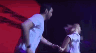 a man is holding a woman 's hand while dancing on a stage .