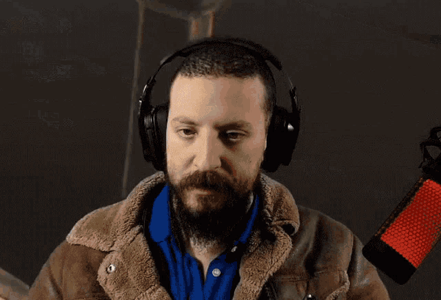 a man with a beard is wearing headphones and a jacket