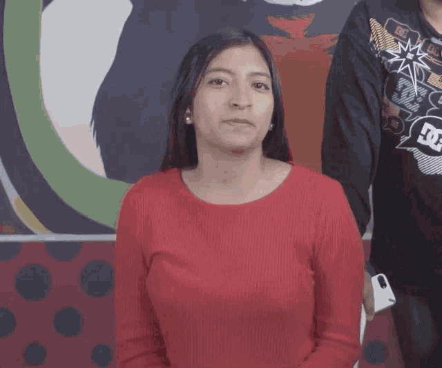 a woman wearing a red sweater with a dc logo on her shirt