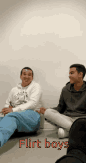 two men are sitting on the floor with the words flirt boys written in red