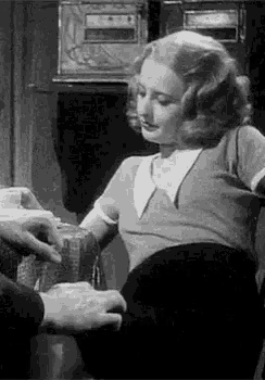 a woman is sitting in a chair with a man 's hand on her lap .