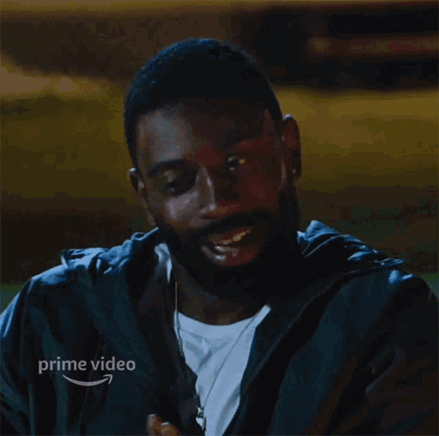 a man in a black jacket says okay in front of an amazon prime video logo