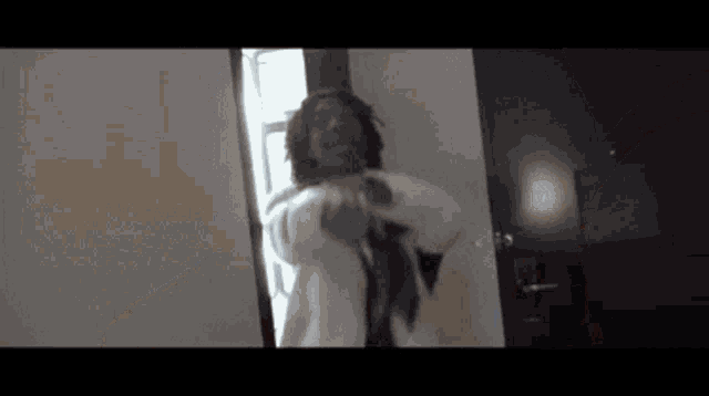 a man in a robe is standing in a doorway .